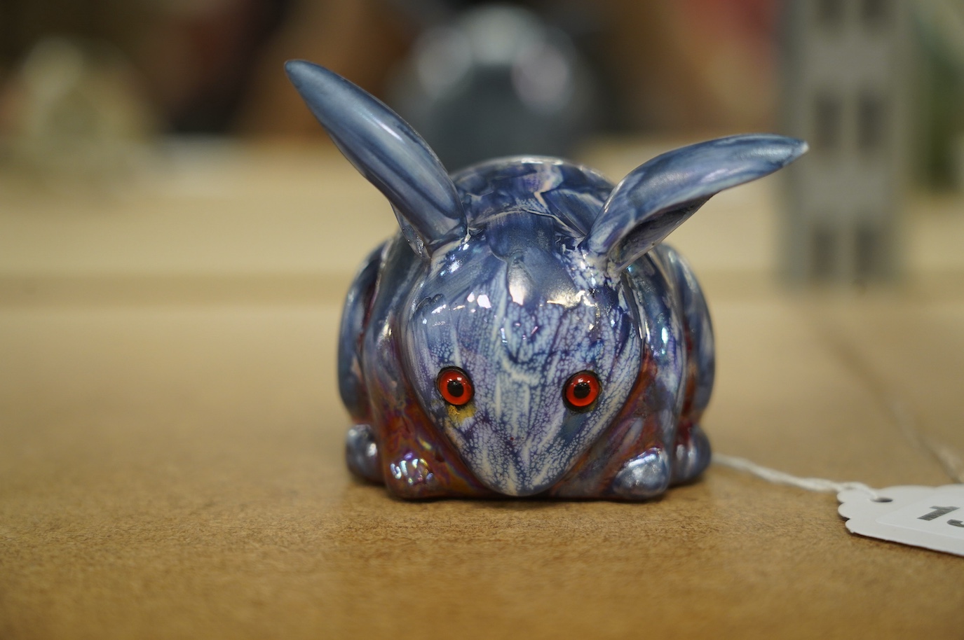 A Bernard Moore blue lustre rabbit with red glass eyes, c.1910, signed, 6cm high. Condition - good